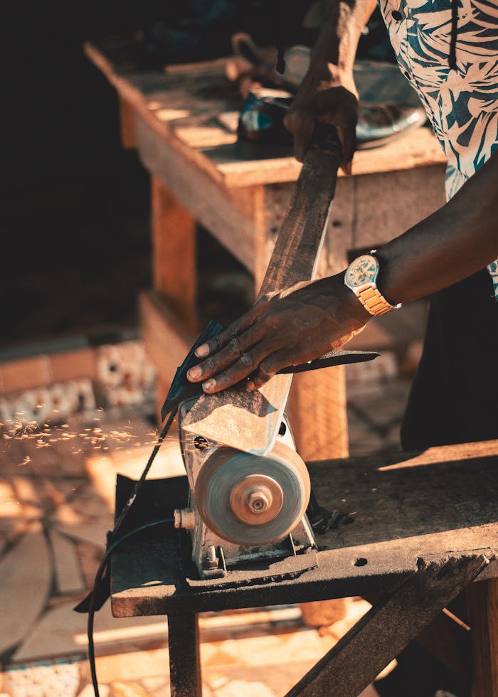 Close-up of an artisan grinding metal with sparks flying in a workshop setting.