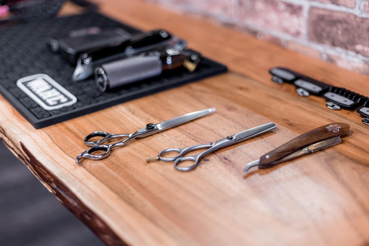 High-quality barber tools arranged on a rustic wooden table in a modern salon.