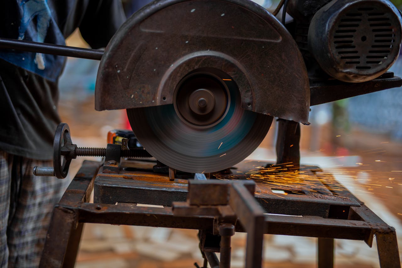 Close-up of a circular saw blade cutting metal, emitting sparks, in an industrial setting.
