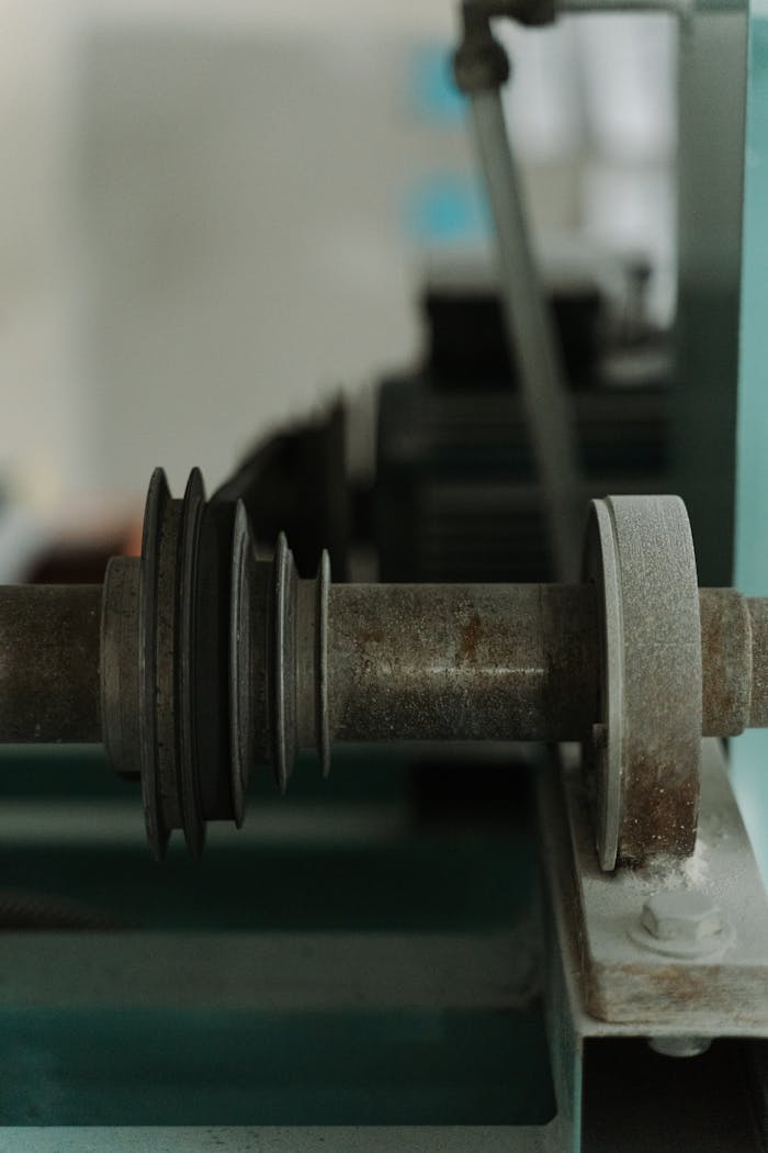 Detailed view of a metal shaft and pulley in industrial machinery, showcasing precision engineering.
